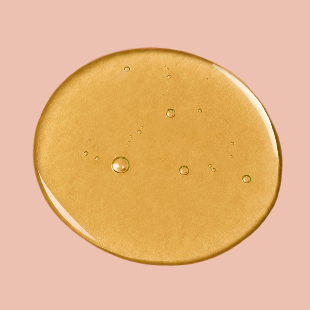 Gold circular object with bubbles on a pink background