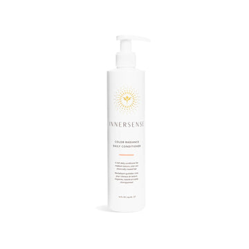 A tall white pump bottle of Innersense Color Radiance Daily Conditioner with a gold sunburst logo, centered on a clean white background.