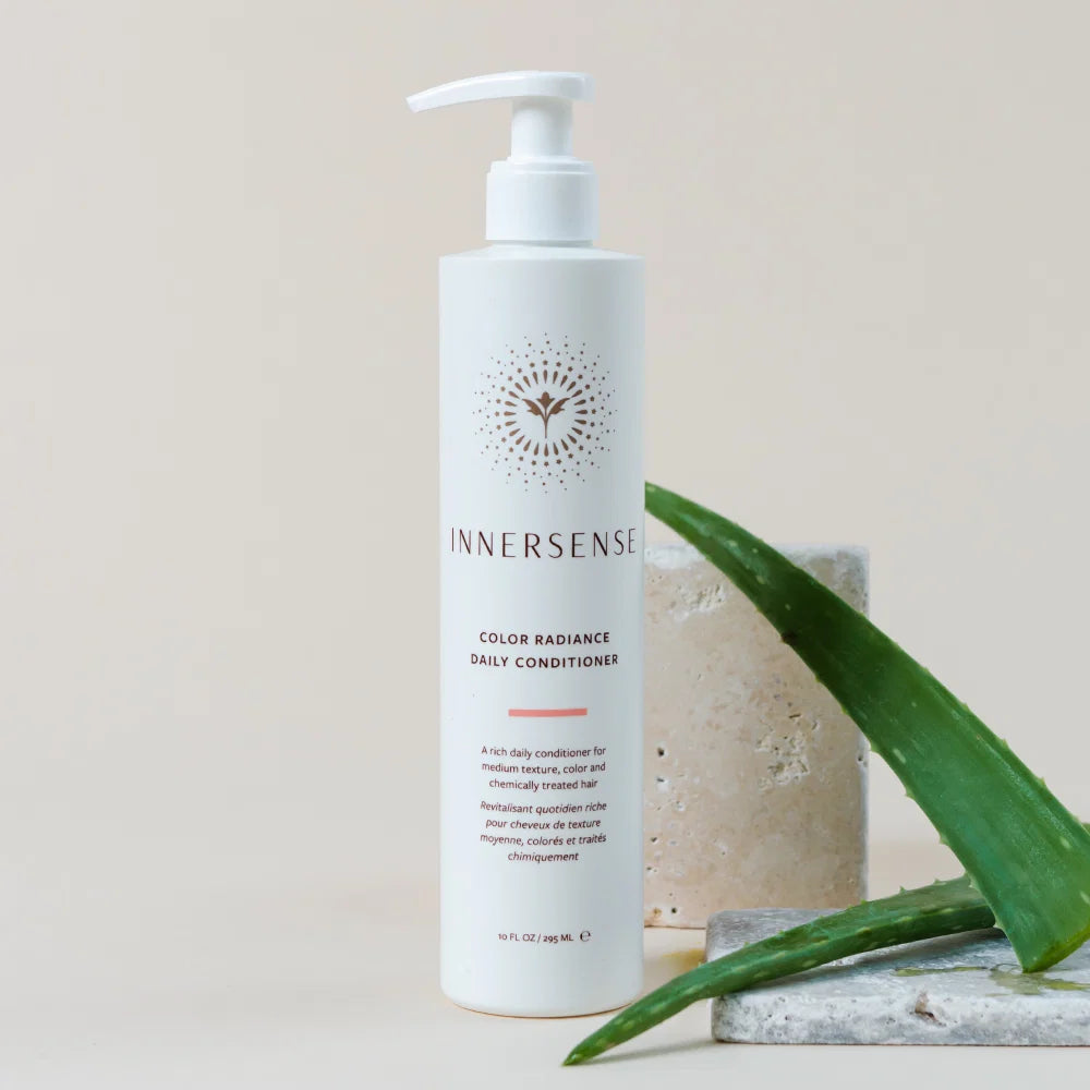 Innersense daily conditioner bottle with aloe vera leaves on a neutral background