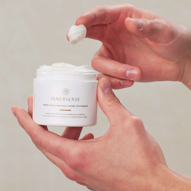 Person holding a jar of Innersense cream with a small amount on a指尖