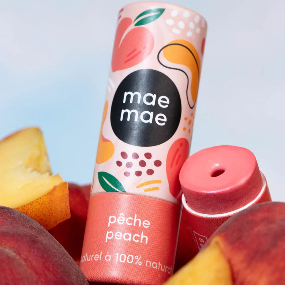 Peach-themed drink container with 'mae maé' branding surrounded by peaches on a gradient background