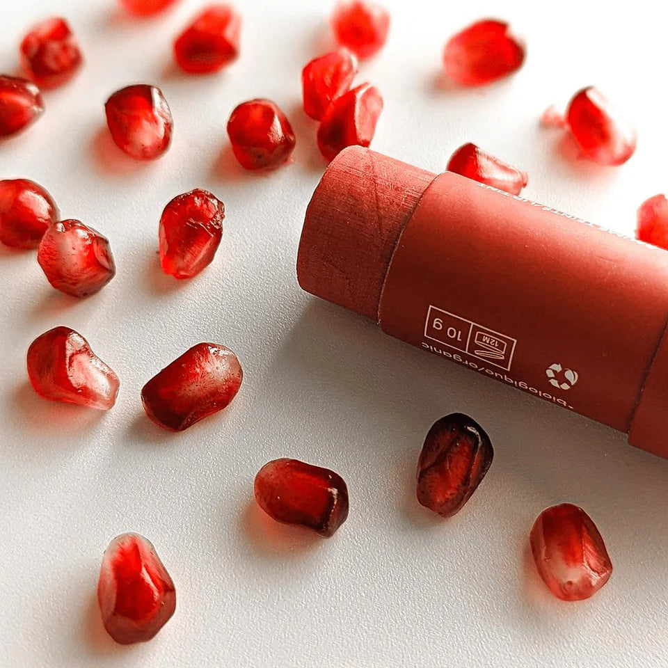 Red pomegranate seeds with a red lipstick on a white background