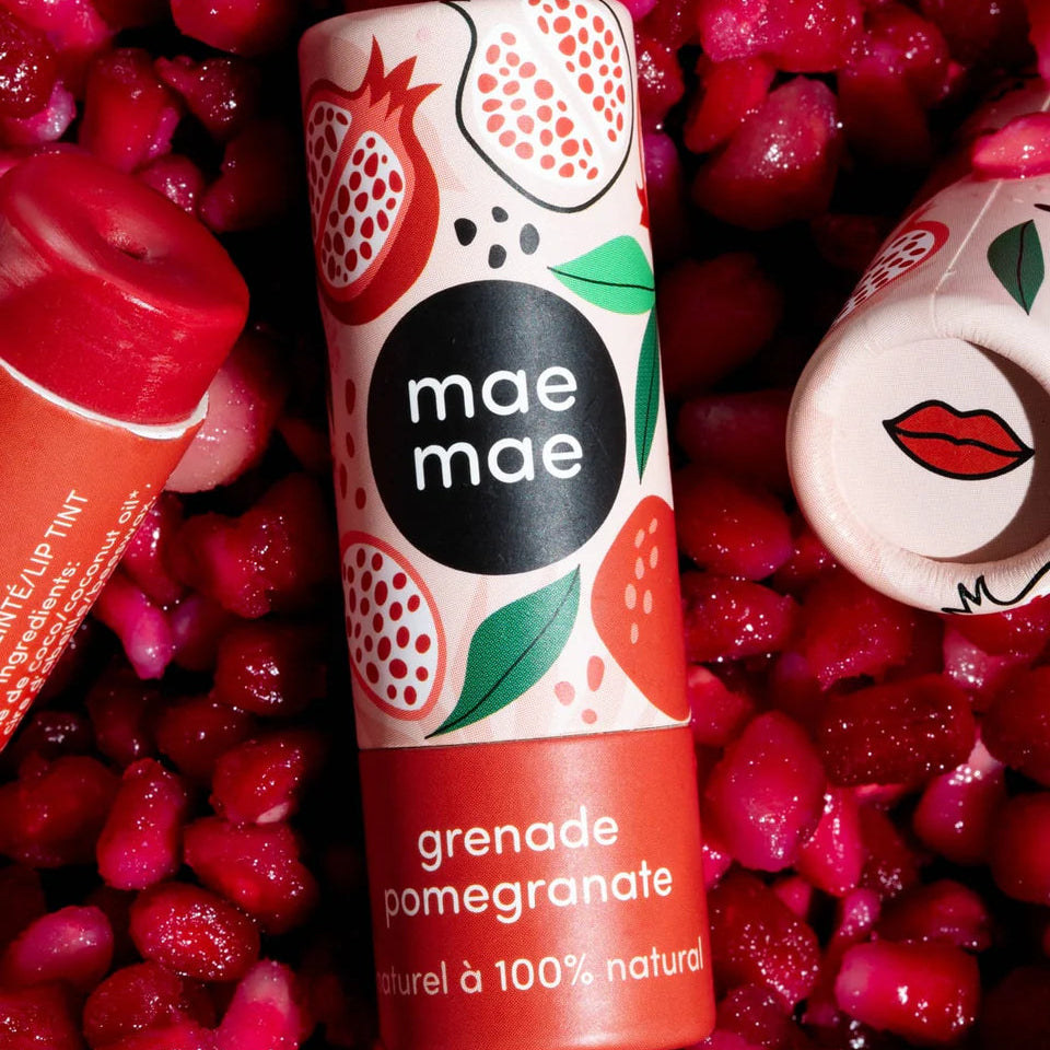 Lip balm with 'mae mae' branding on a background of pomegranate fruits