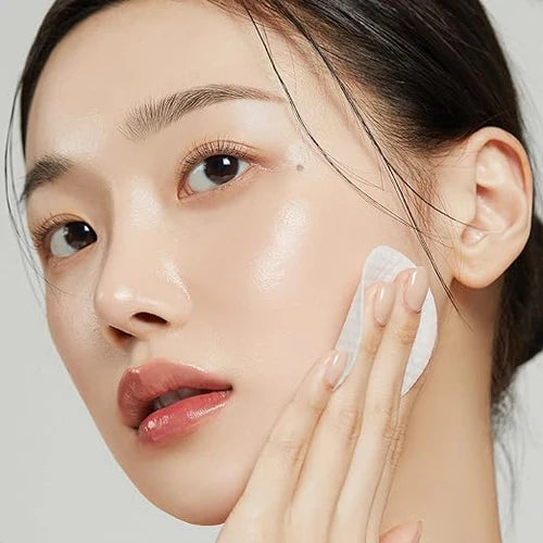 Woman applying a skincare product to her face with a neutral background