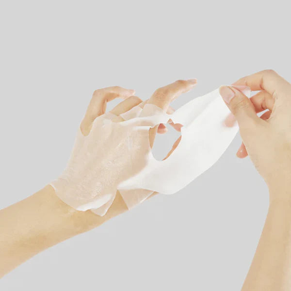 Hands unfolding the MEDIHEAL The E.G.T Nourishing Ampoule Mask sheet to show the mask texture and application format.