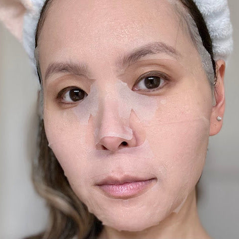 Person with a towel on their head against a neutral background