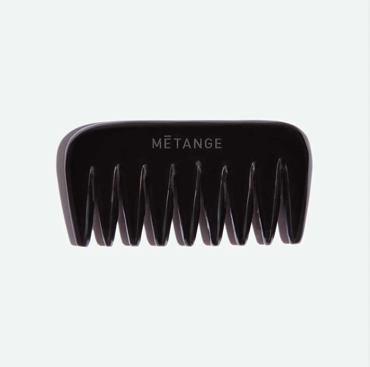 Black comb with 'Métange' branding on a light gray background
