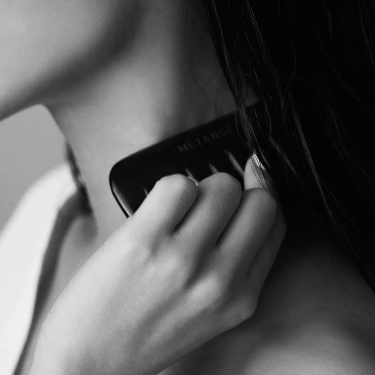 Black makeup compact held by a hand against a neutral background