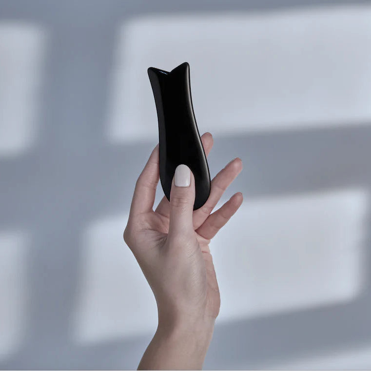Hand holding a black smartphone with a reflective screen against a light background