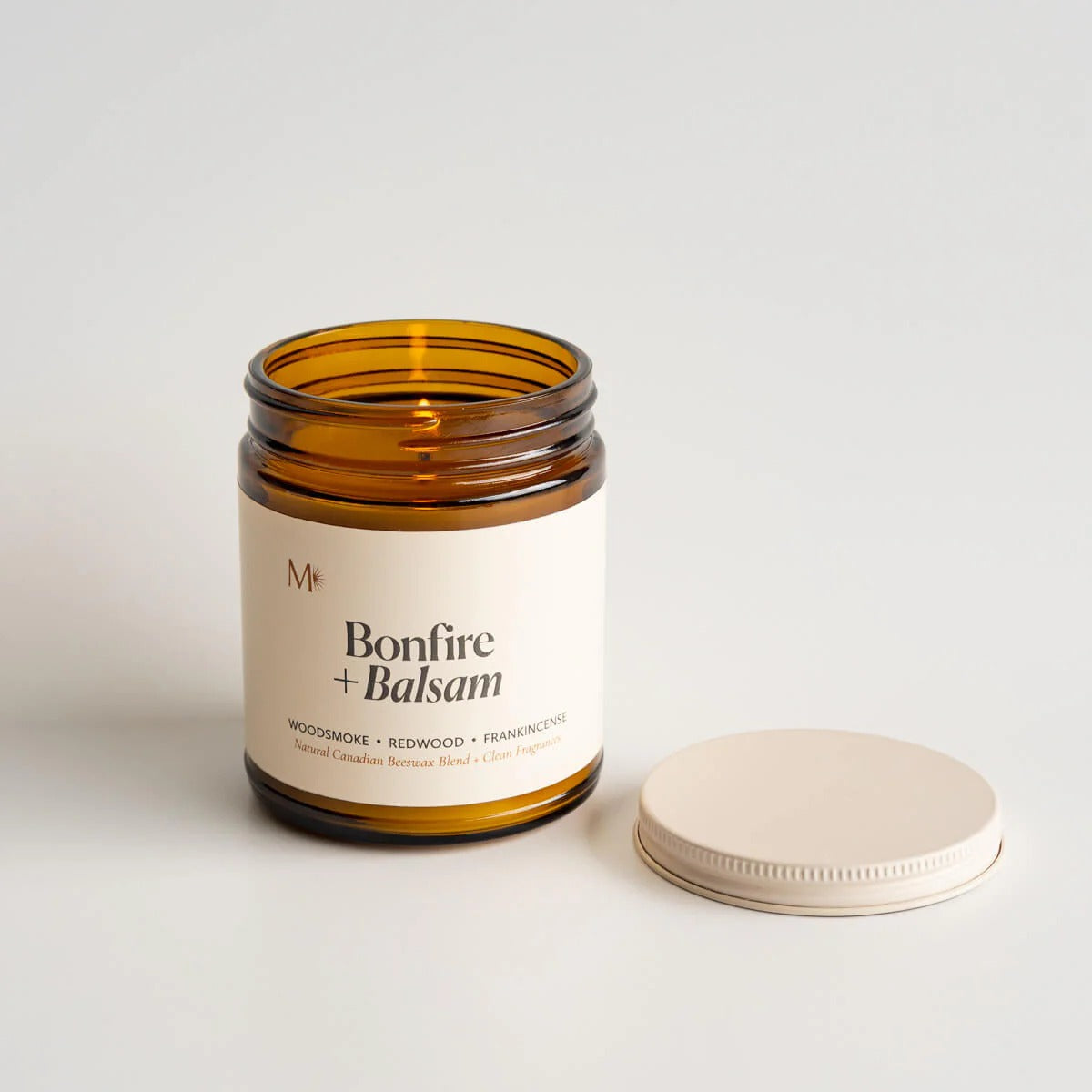 Candle jar labeled 'Bonfire + Balsam' with a white label on a light background