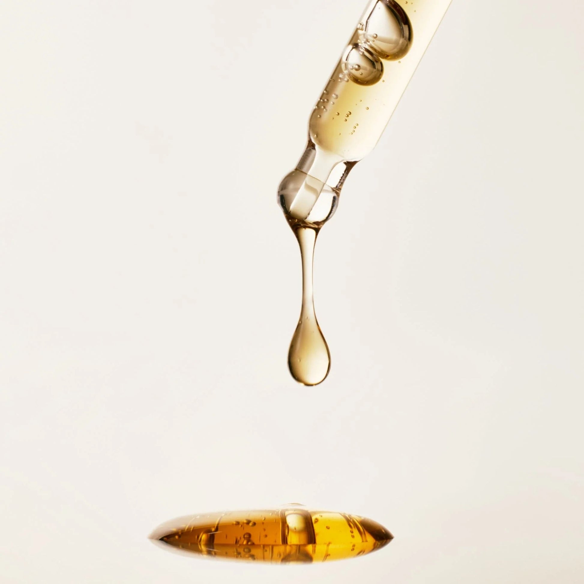 Close-up of a dropper with a yellow liquid on a light gray background