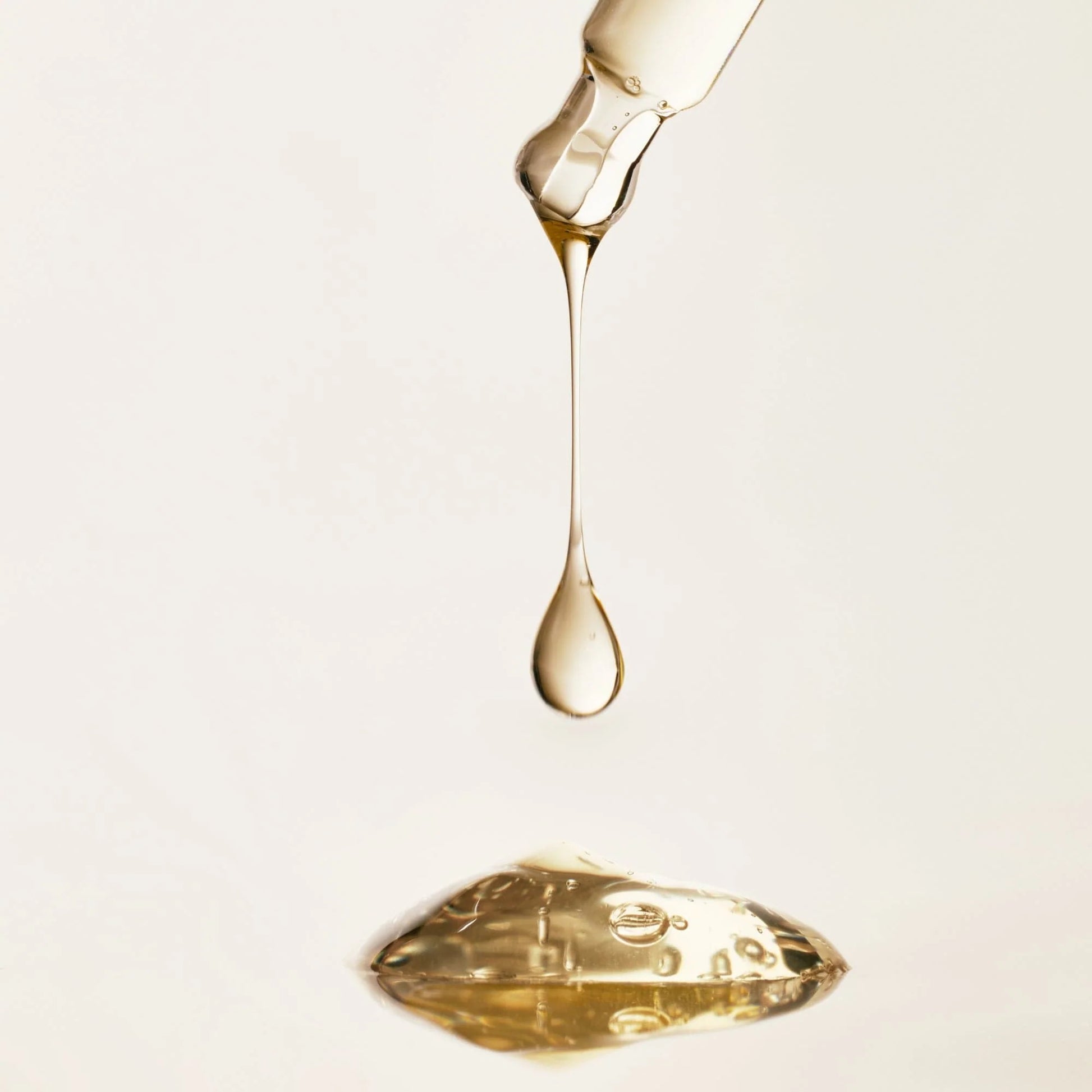 Gold liquid being dripped onto a white surface