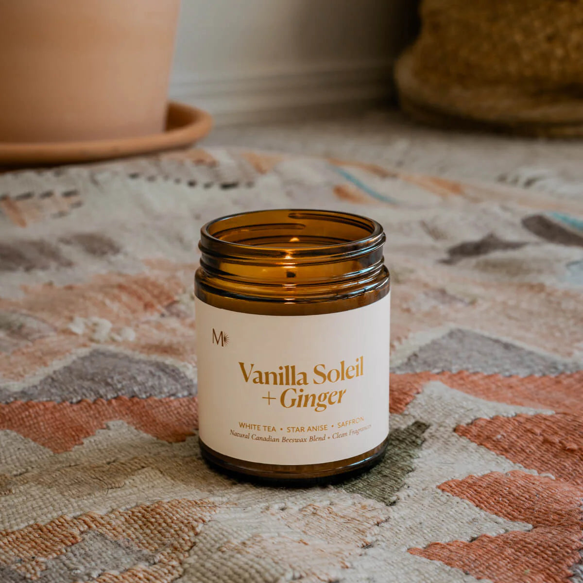 Vanilla Soleil + Ginger candle in a brown jar on a patterned surface