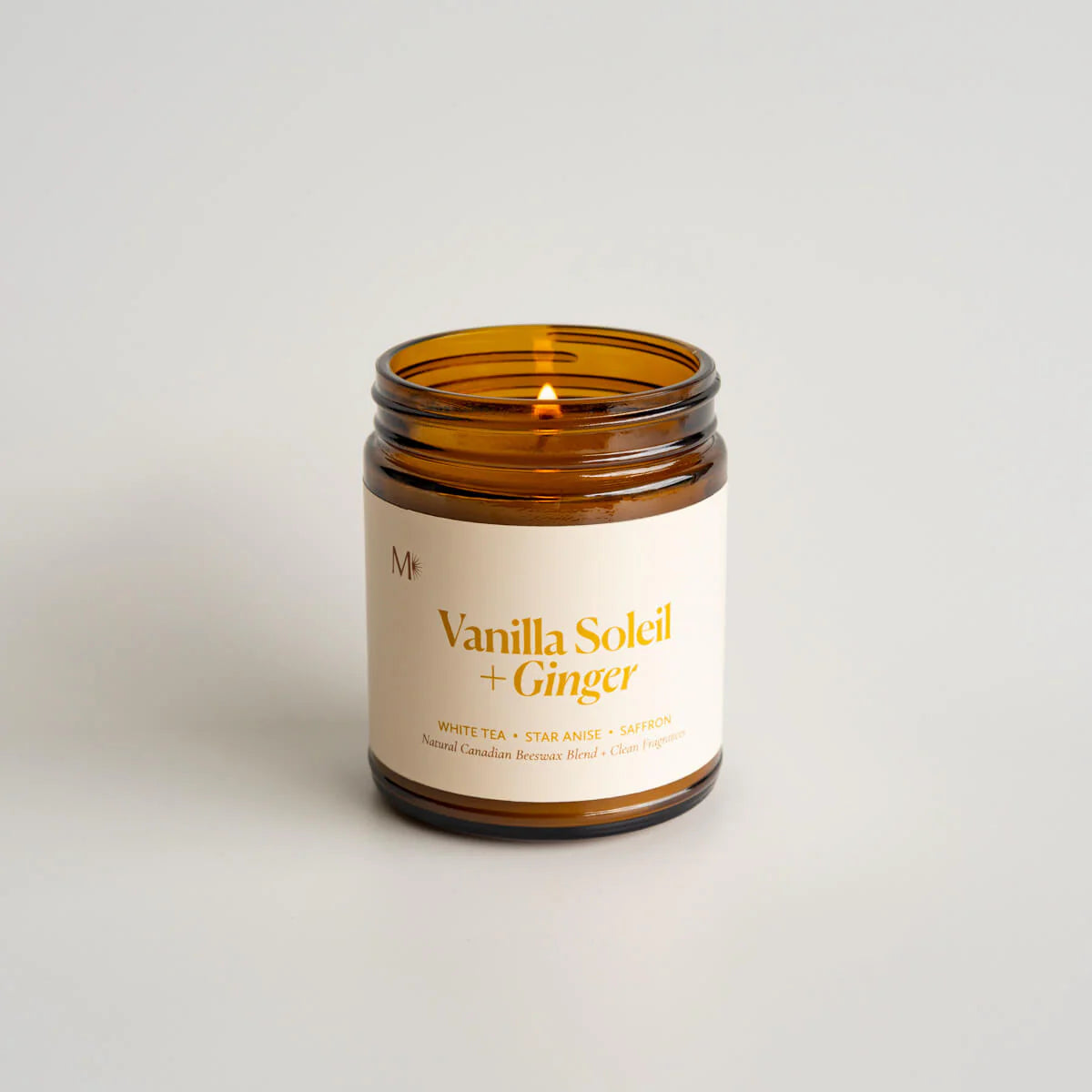 Vanilla Soleil + Ginger candle in an amber jar on a light background