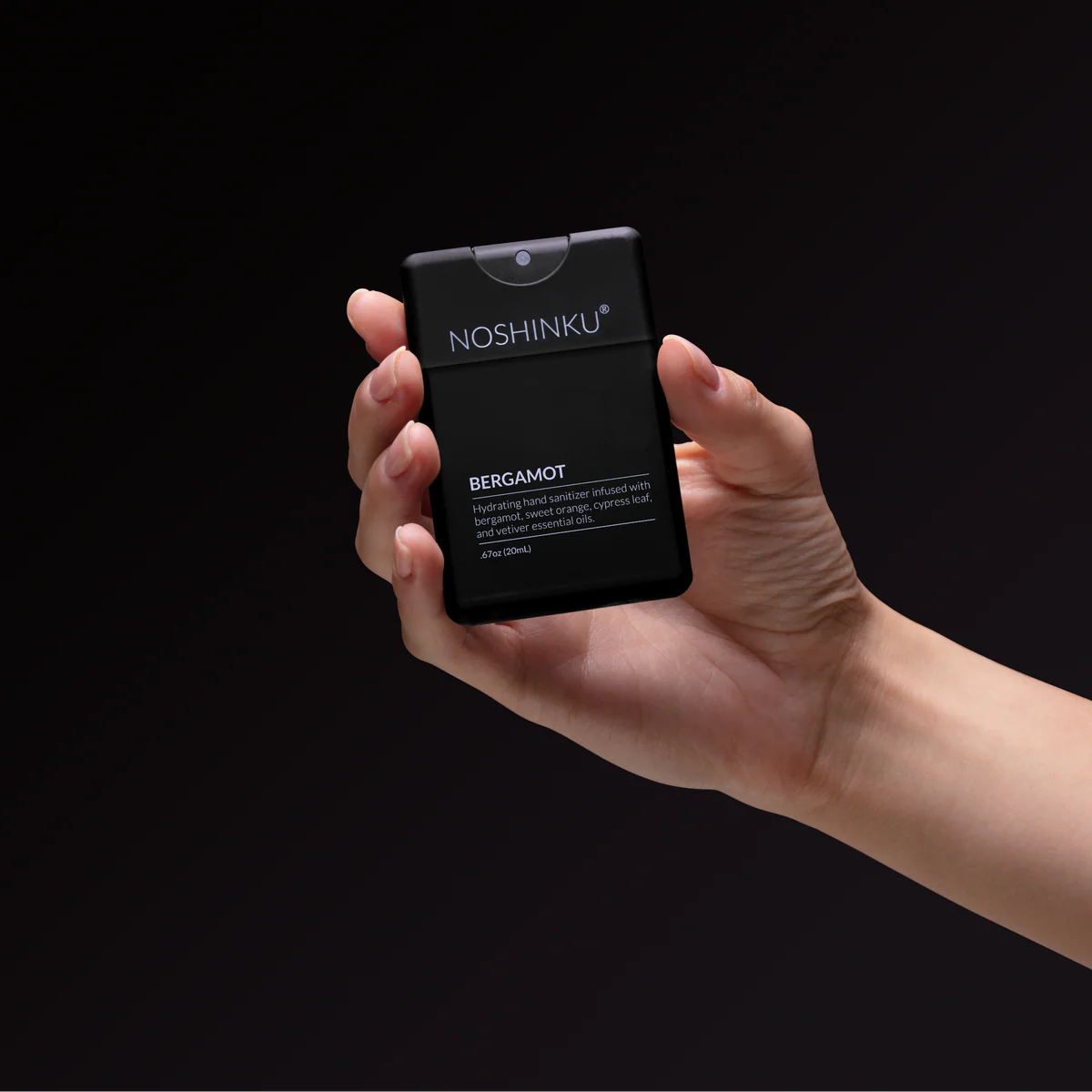 Hand holding a black Noshinku product against a dark background