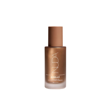 NUDA Glowing Face Oil in a frosted glass bottle with a metallic bronze cap, centered on a plain white background.