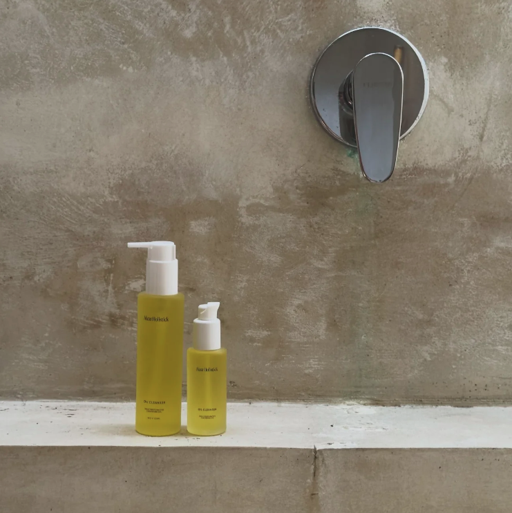 Two yellow bottles with white caps on a concrete surface with a shower handle in the background.