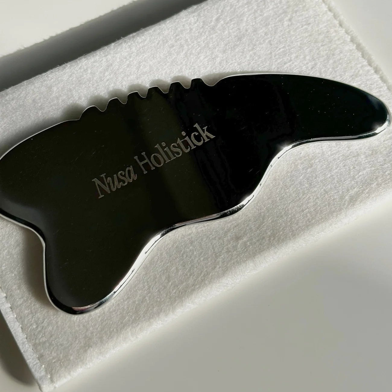 Black gua sha tool on a white background