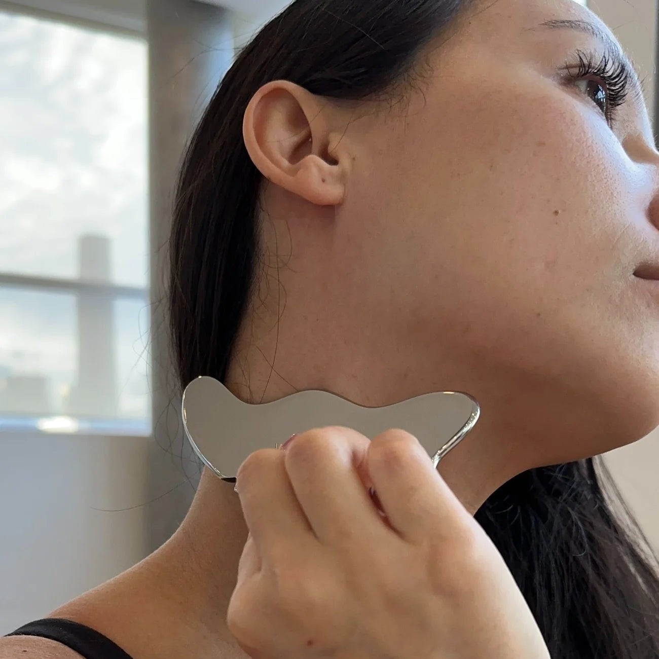 Woman using a gua sha tool on her neck