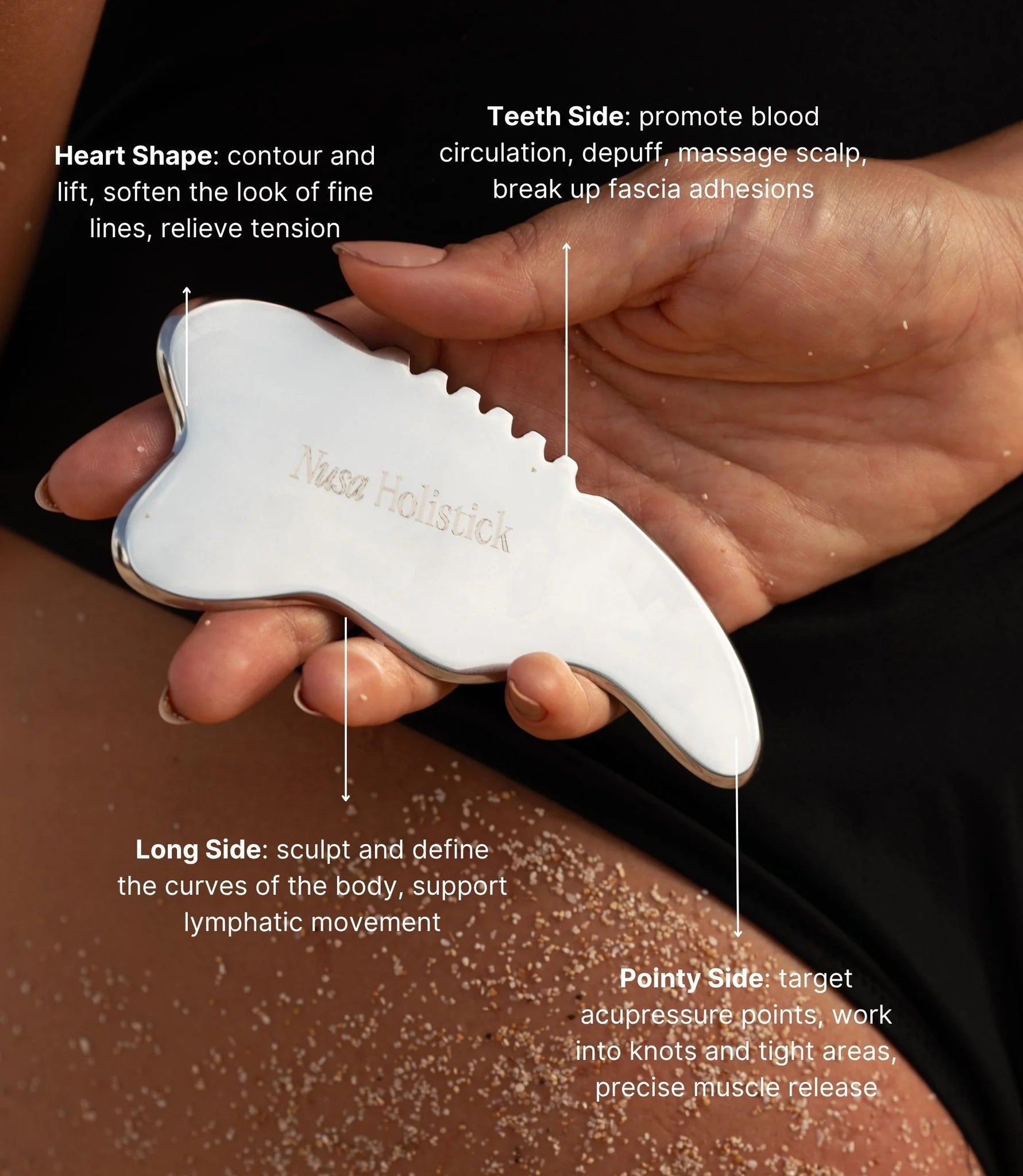 Hand holding a white gua sha tool with labeled benefits on a dark background