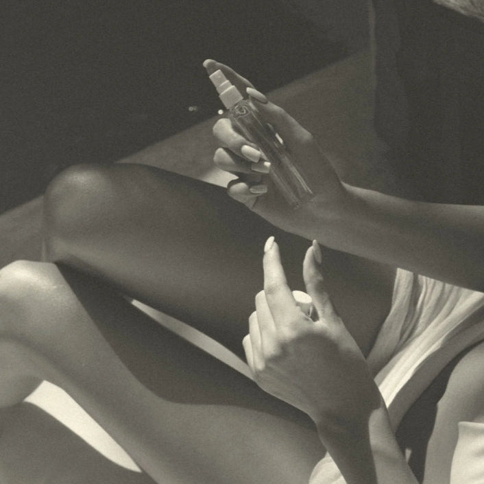 Black and white photo of a person sitting on a beach with a butterfly on their leg.