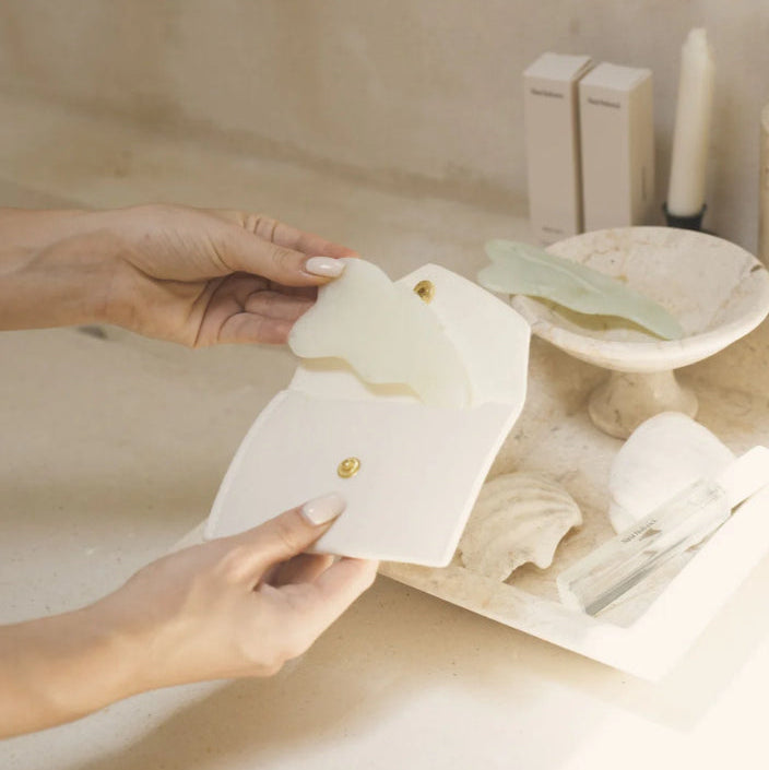 Person holding a white card with a gold emblem over a sink in a bathroom setting.