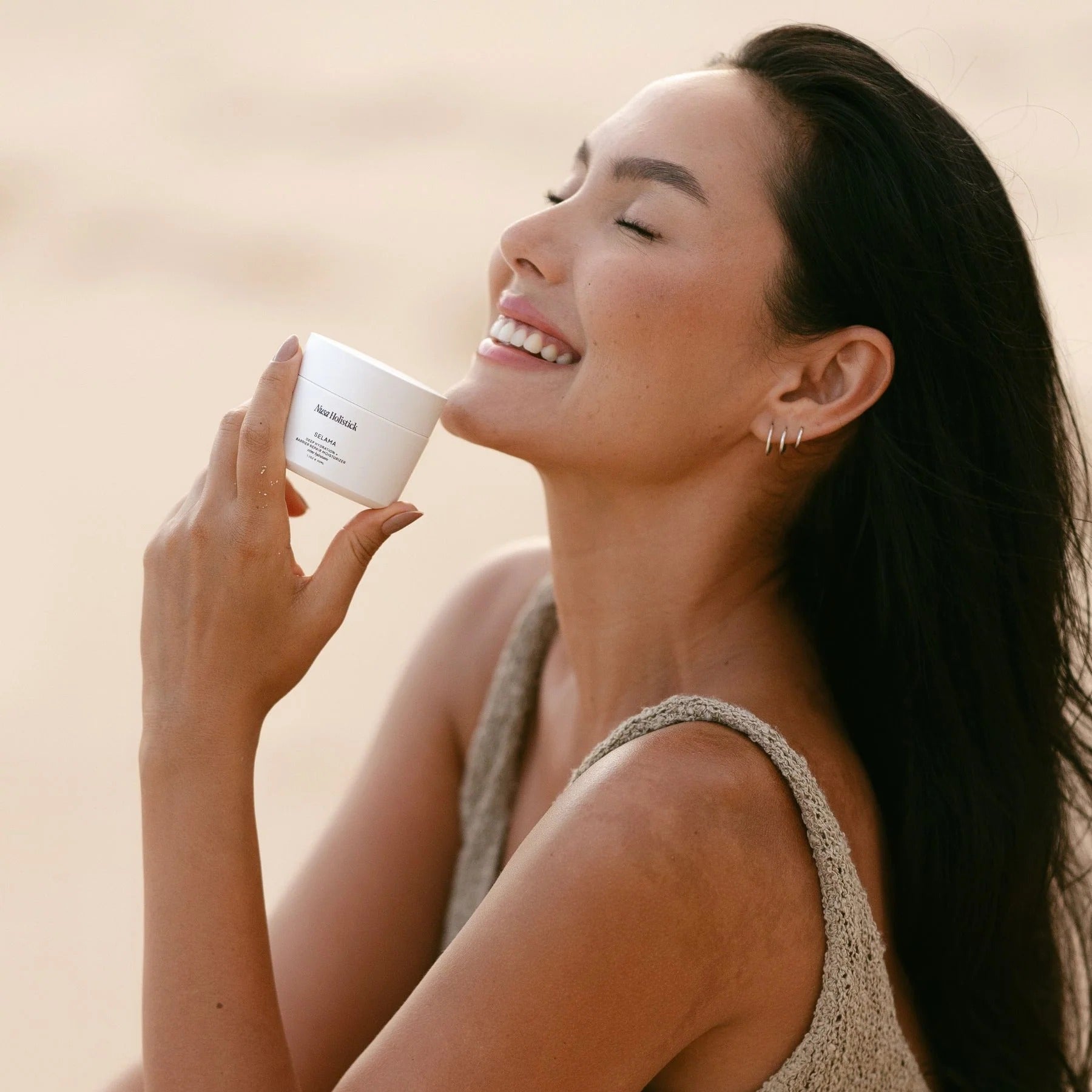Woman holding a white container with a brand logo against a beige background