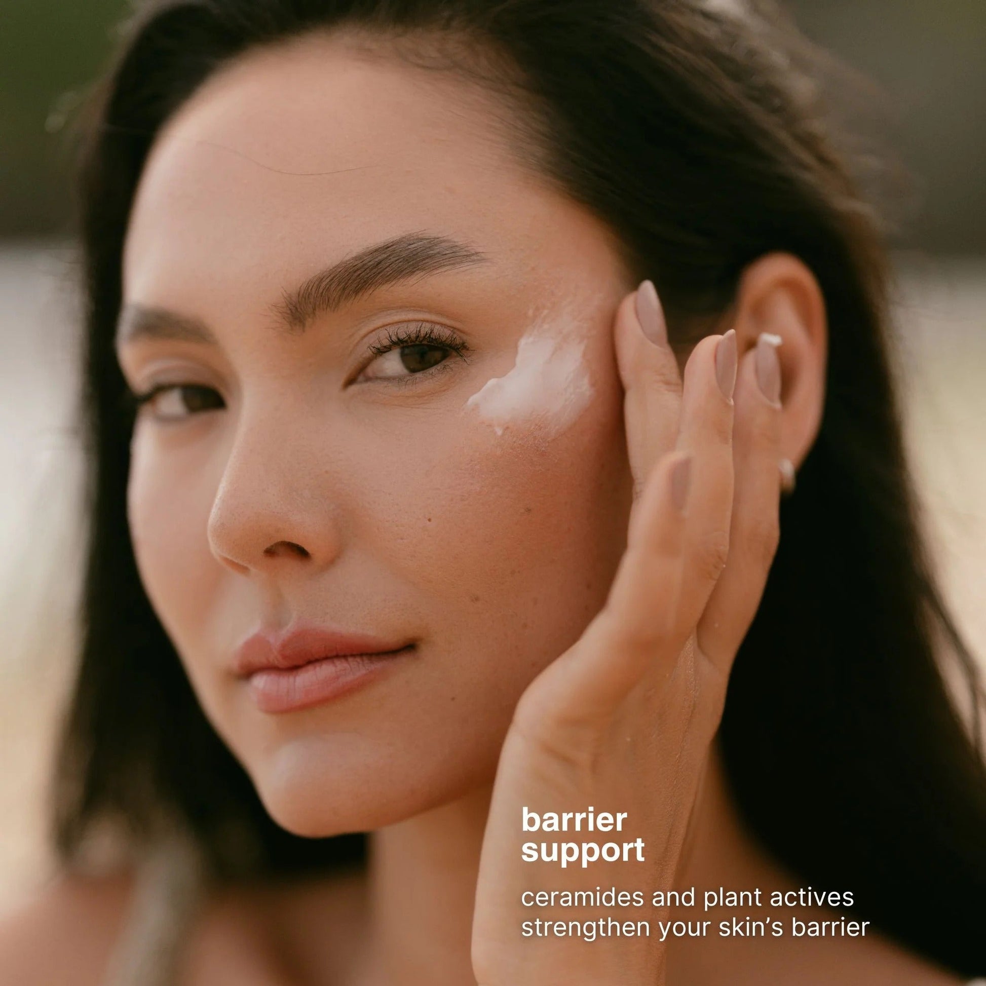 Woman applying cream to her face with a blurred background