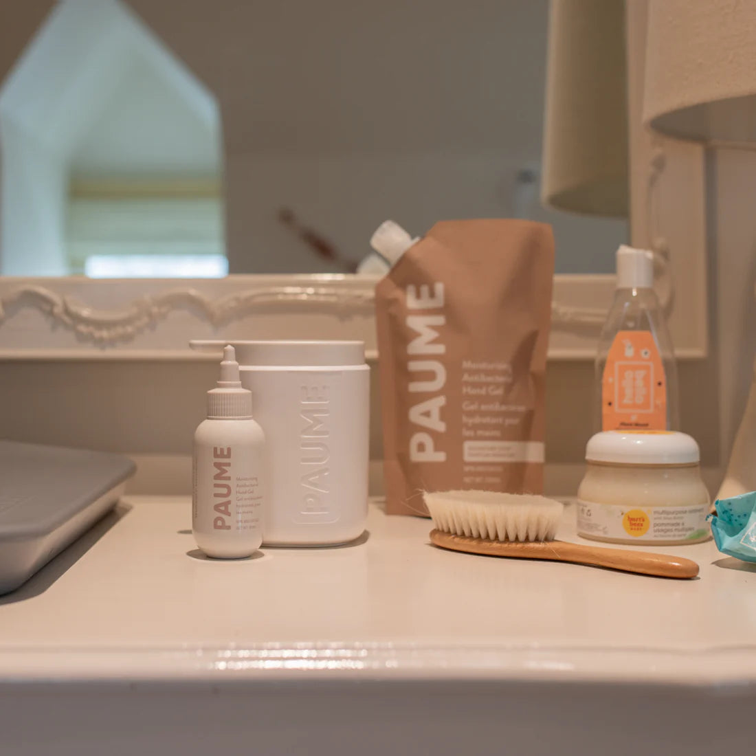 Bathroom counter with PAUME products including bottles, a brush, and a bag.