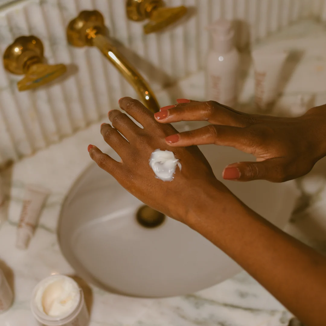 Person applying cream to hands in a bathroom setting