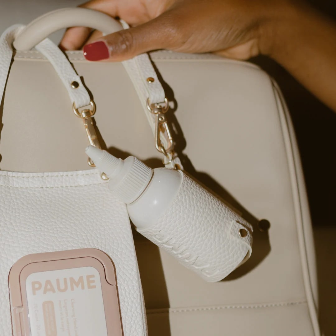 Beige handbag with a textured white bottle holder attached, featuring the brand 'PAUME'.