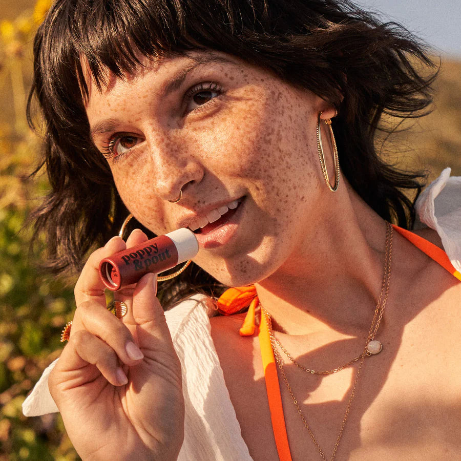 Woman holding a lip balm with a blurred natural background