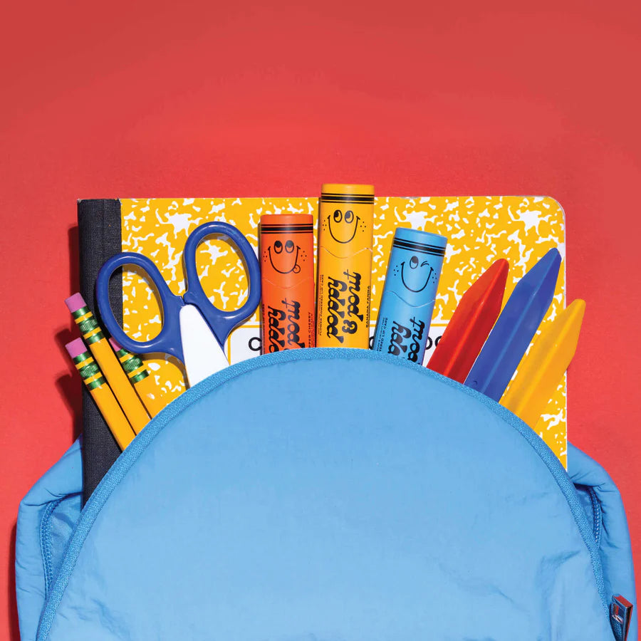 Blue backpack with school supplies including scissors, crayons, and markers on a red background