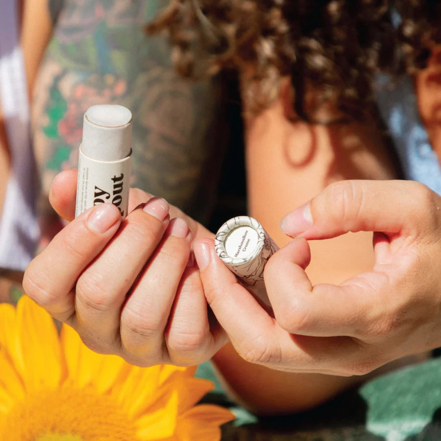 Two people holding small bottles with visible text against a blurred natural background