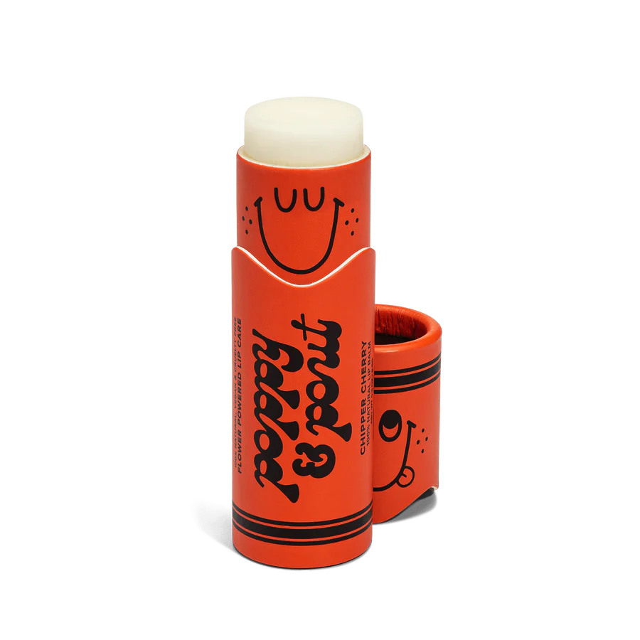 Orange lip balm with a smiley face design on a white background