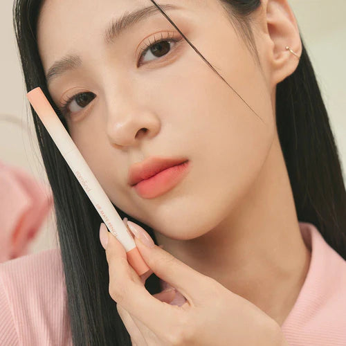 Close-up of a person holding a makeup pencil near their face