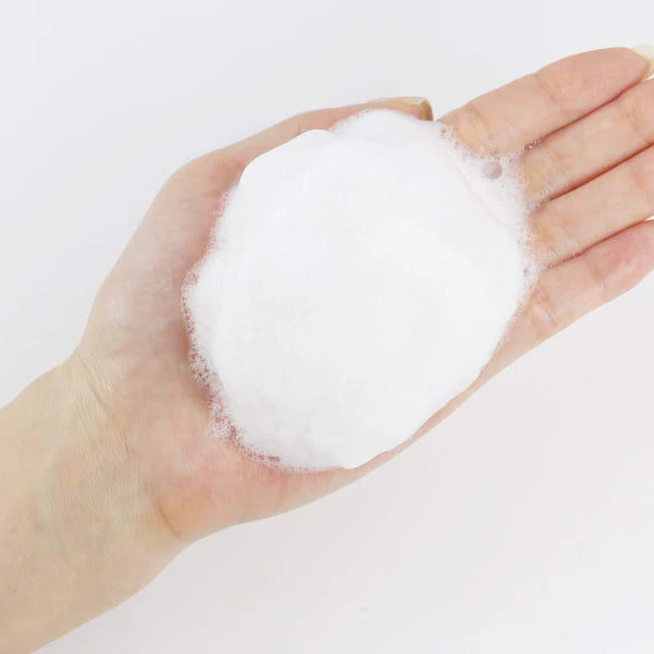 Hand holding a ball of white foam on a light gray background