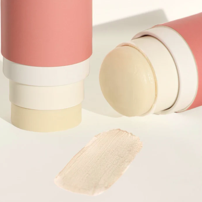Cosmetic stick with pink casing and beige tip on a light background