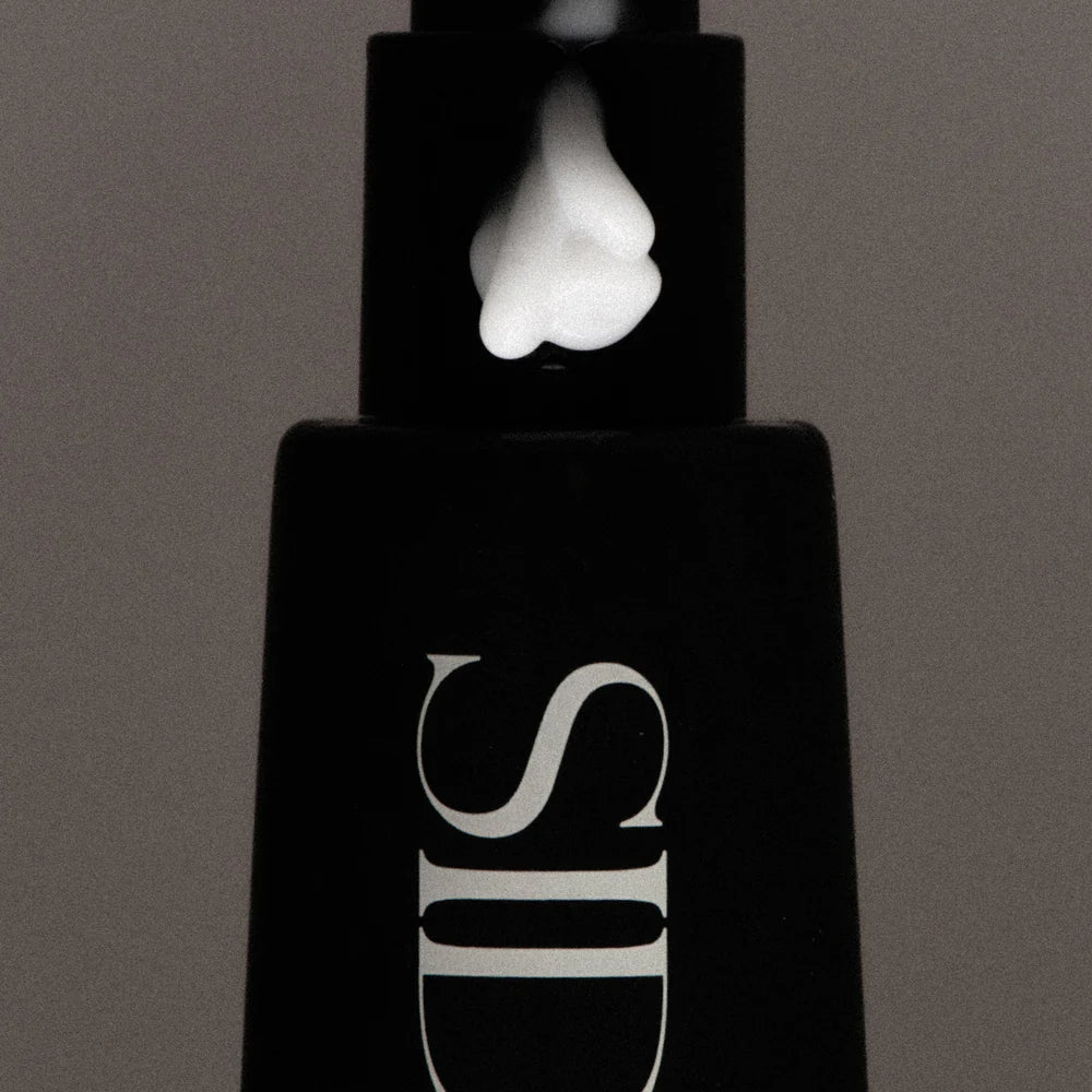 Black cosmetic bottle with a white cap on a gray background