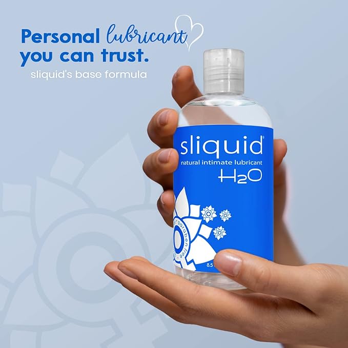 Hand holding a bottle of sliquid H2O lubricant against a light blue background