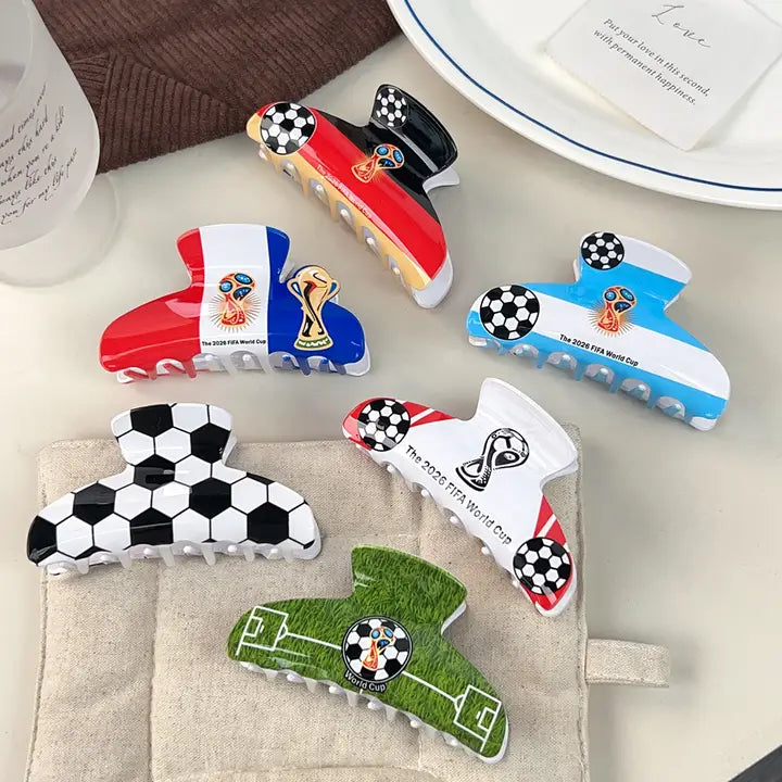 Collection of World Cup-themed hair clips on a table with a cup and plate in the background.