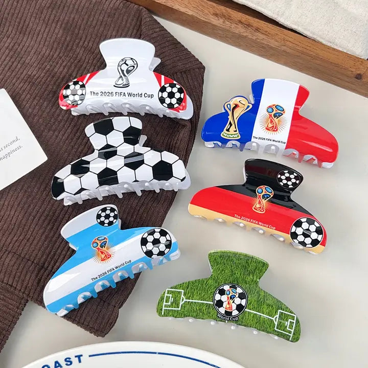 Collection of World Cup-themed hair clips on a surface with a brown fabric background.
