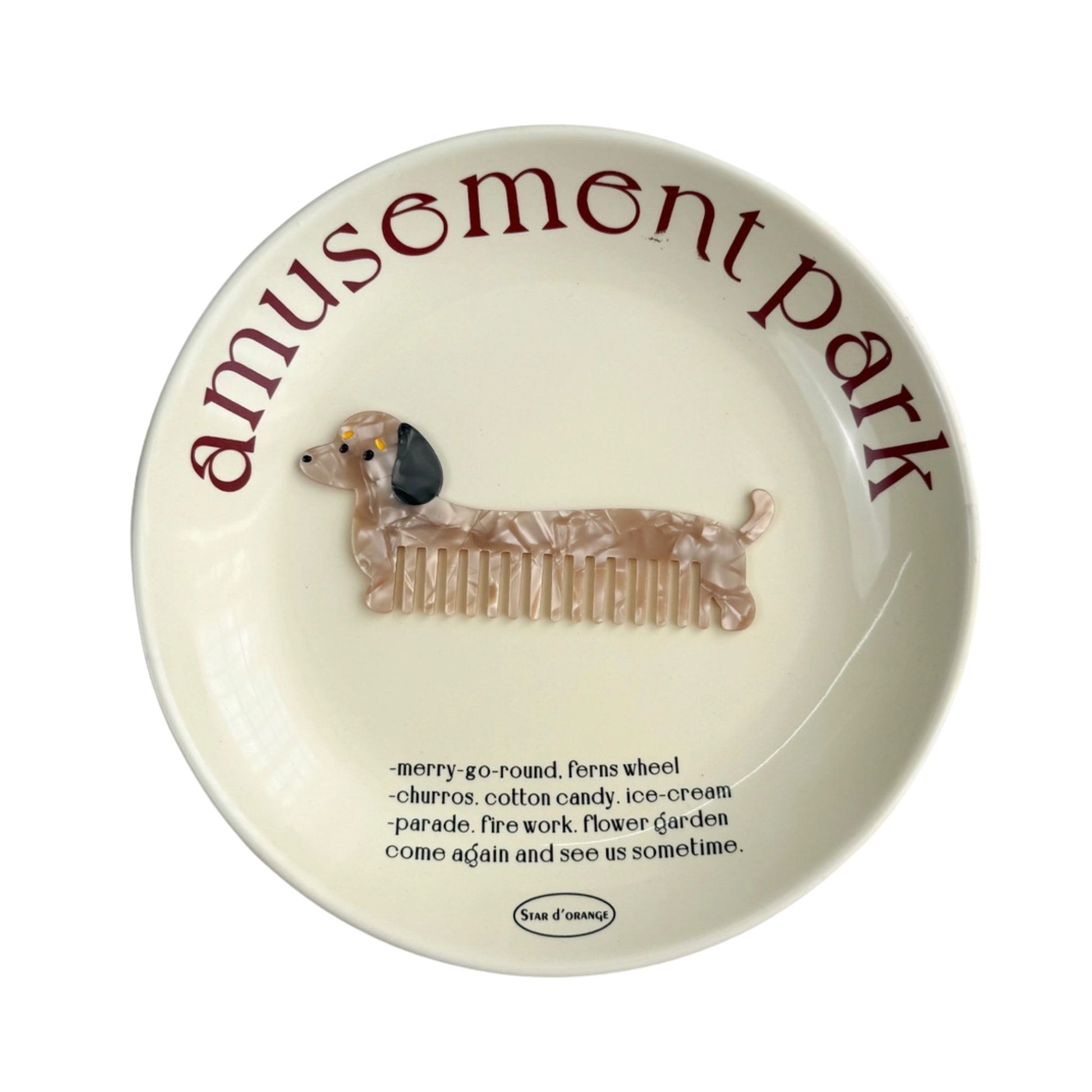 Round ceramic plate with a dachshund illustration and 'Amusemont Park' text on a white background