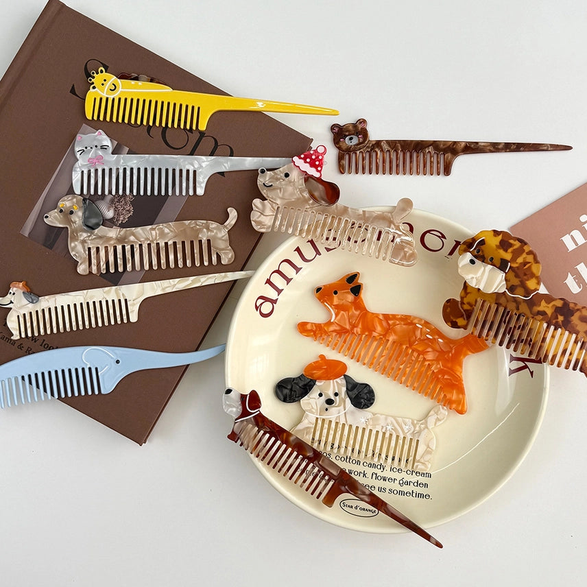 Collection of novelty animal-themed combs on a white surface with a decorative plate featuring a dog illustration.
