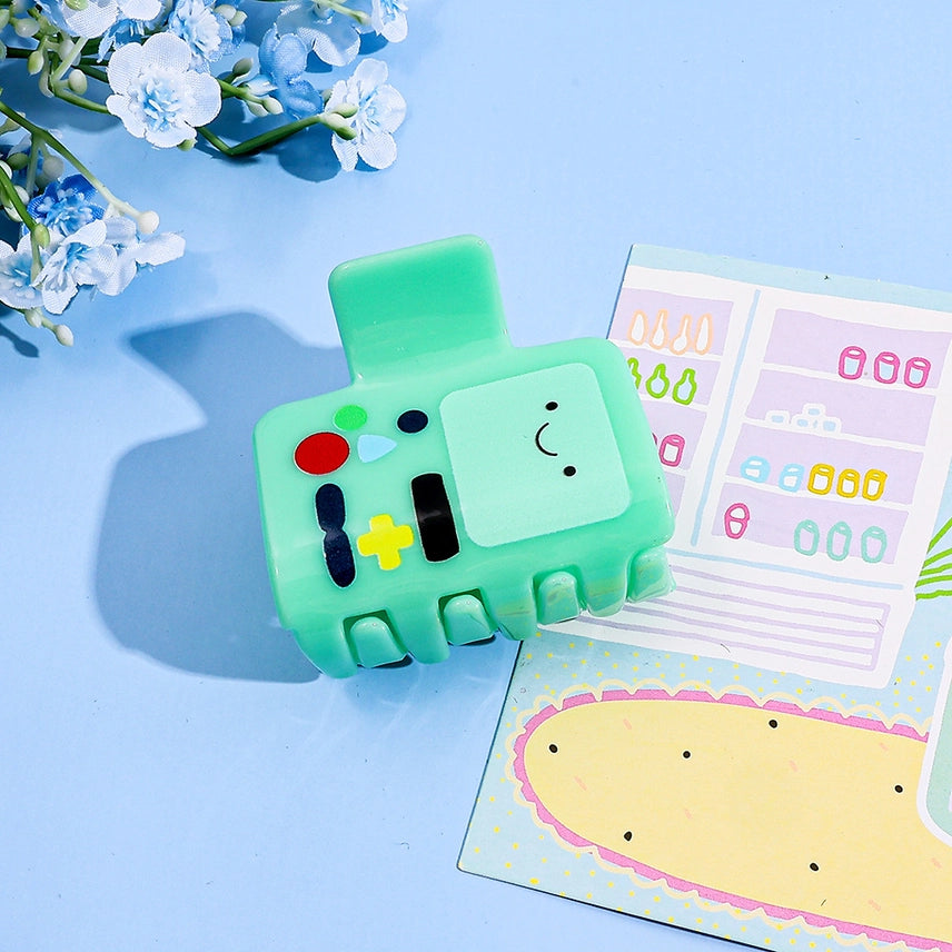 Green toy resembling a game controller with cartoon face on a white background