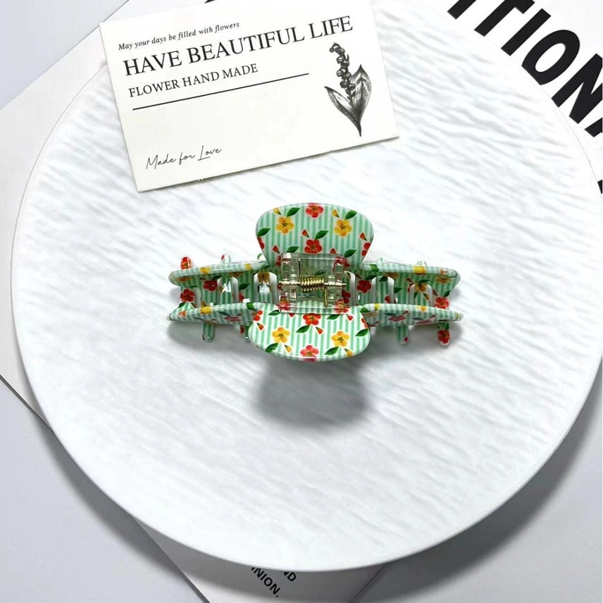 Floral patterned hair clips on a white surface with a card in the background.