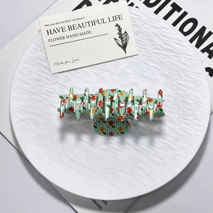 Decorative hair clip with floral design on a white surface with a card reading 'Have Beautiful Life'.