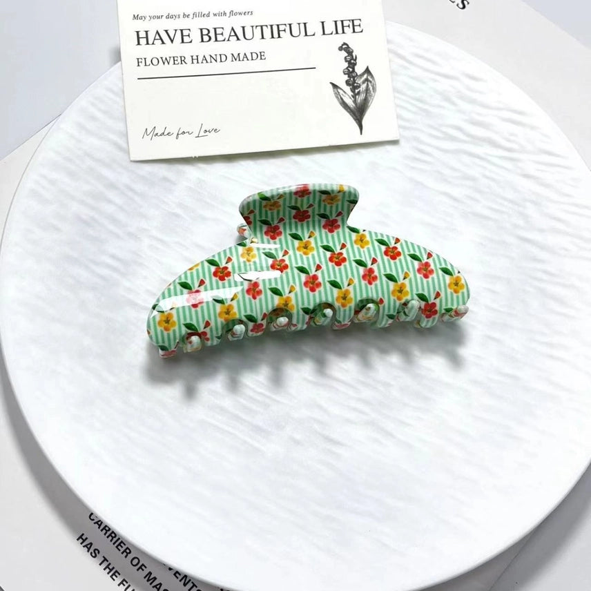 Floral patterned hair clip on a white plate with a card in the background