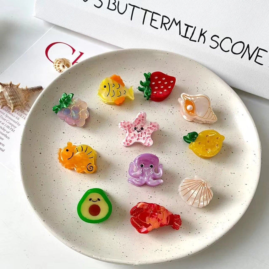 Colorful food-shaped erasers on a speckled plate with a magazine in the background.