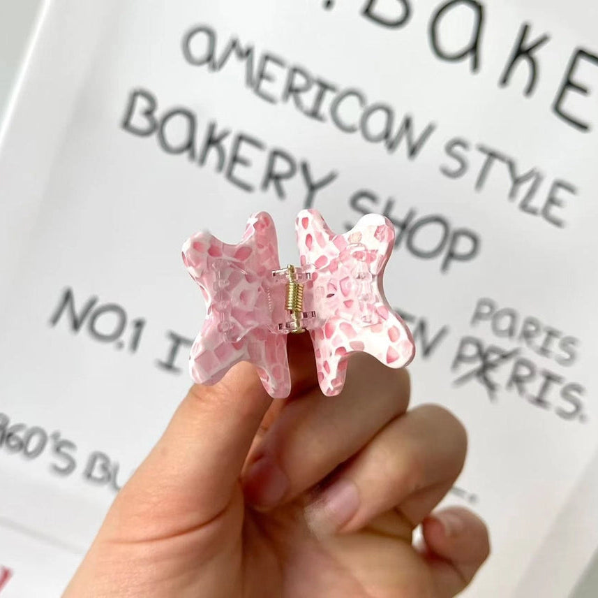 Pink star-shaped earrings held in front of a bakery-themed background
